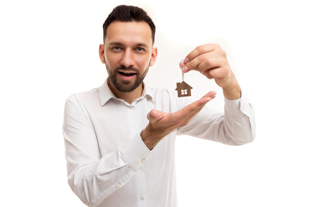 a man realtor in a white shirt is demonstratively holding a keychain from a house in his hands, Concept of property insurance, real estate services, bank lending of residential and commercial real - Fotó, kép