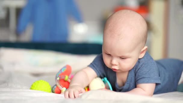 Jouets actifs pour bébé de 5 mois. Bébé garçon bébé jouant avec des jouets en développement couché sur le canapé. - Séquence, vidéo