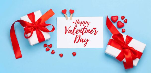 Valentines day greeting card. Gift boxes, heart decor and candy sweets over blue background. Top view flat lay - Foto, Imagem