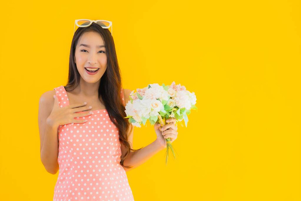 Portré gyönyörű fiatal ázsiai nő színes virág sárga elszigetelt háttér - Fotó, kép