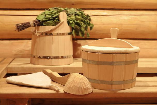 Tradycyjne akcesoria do sauny i miotła brzozowa znajdują się na drewnianych ławkach we wnętrzu łaźni.  - Zdjęcie, obraz