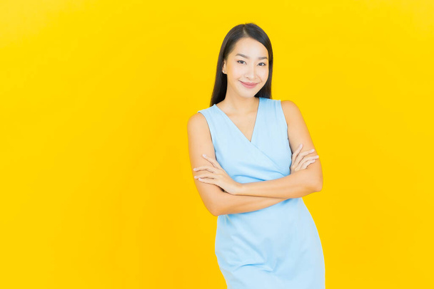 Retrato hermosa joven mujer asiática sonrisa con acción sobre fondo de color amarillo - Foto, imagen