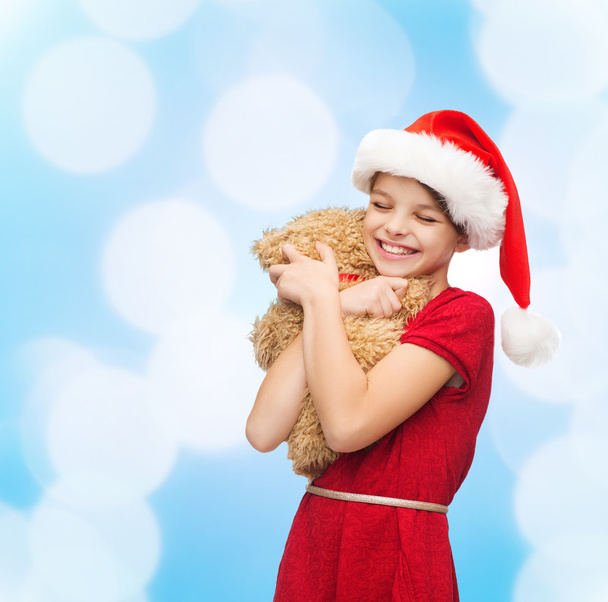 smiling girl in santa helper hat with teddy bear - Valokuva, kuva
