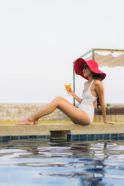 Portret jonge aziatische vrouw blij glimlach ontspannen rond buitenzwembad in hotel resort voor reizen vakantie - Foto, afbeelding