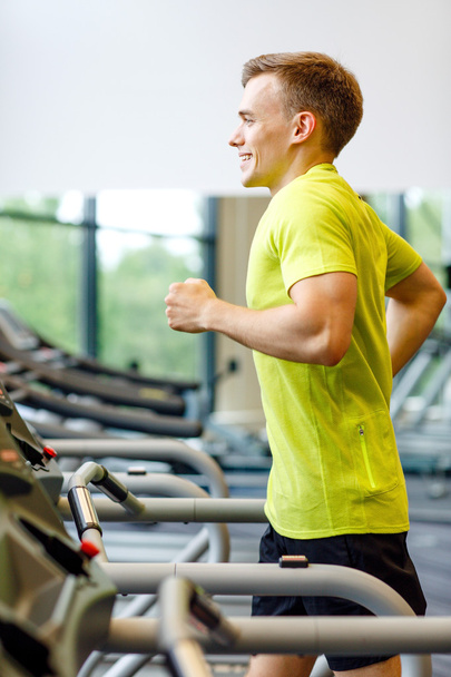 smiling man exercising on treadmill in gym - Zdjęcie, obraz