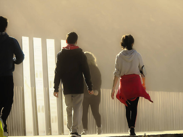 Ihmiset kävelevät meren rannalla aurinkoisena talvipäivänä. - Valokuva, kuva