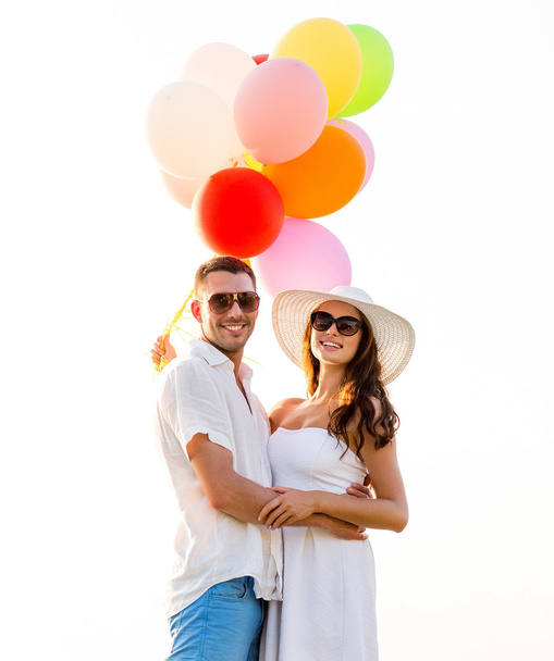 smiling couple with air balloons outdoors - Foto, afbeelding