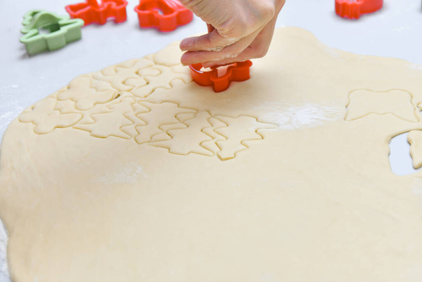 L'enfant fait des biscuits à partir de la pâte roulée à l'aide de moules spéciaux. - Photo, image