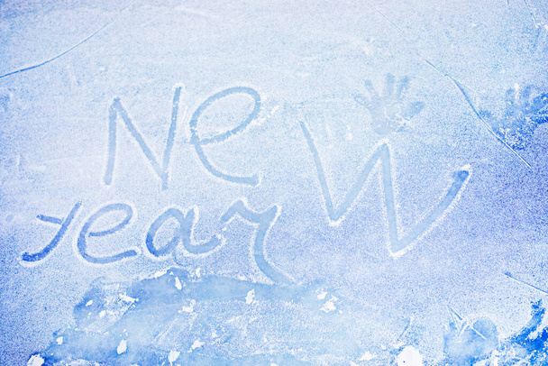 text happy new year written on ice for skating with handprints on winter day, Flatlay, horizontal - Foto, Bild