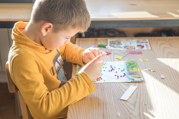 A kisfiú kreatív, hogy házi készítésű csináld magad dinoszaurusz mozaik. A kreativitás támogatása, cselekvéssel történő tanulás, tapasztalatokon keresztüli tanulás. A gyermekek kreatív látásmódhoz való hozzáférésének elősegítése. - Fotó, kép