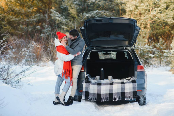 Winter picnic in the forest. Love story in snow. couple in winter play in snow and hugging near the pine. Two lovers on winter walk. Valentine's Day for couple in rustic style. Winter lovestory - Foto, Imagem