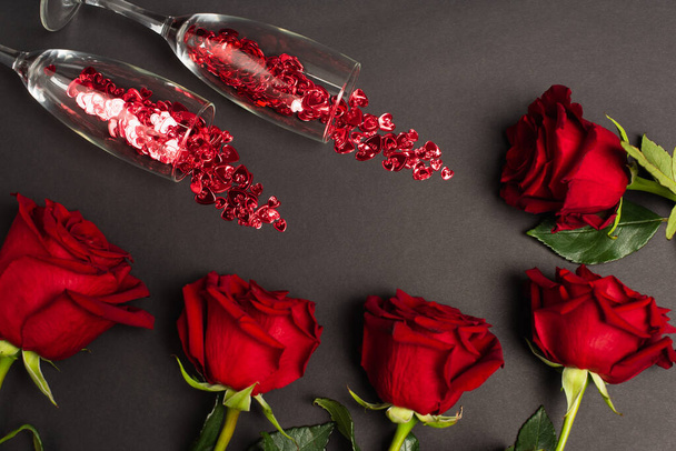 vista superior de rosas rojas cerca de gafas con confeti en negro - Foto, imagen