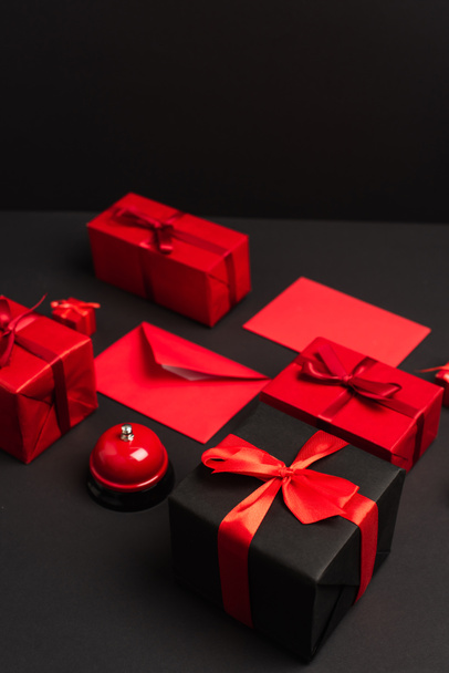 regalos envueltos y sobres cerca de campana metálica en negro - Foto, Imagen