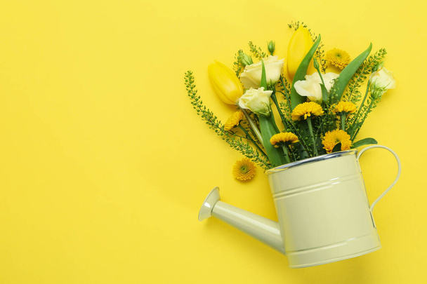 Watering can with flowers on yellow background - Foto, imagen