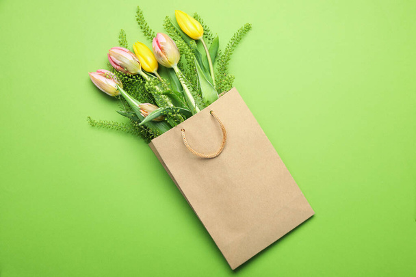 Χάρτινη τσάντα με λουλούδια σε πράσινο φόντο - Φωτογραφία, εικόνα
