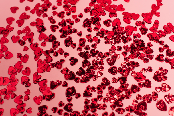 Draufsicht auf leuchtend rote Konfetti-Herzen auf rosa - Foto, Bild