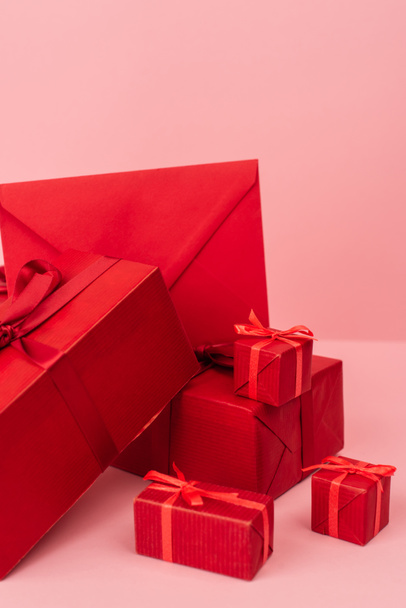 red wrapped gift boxes and envelope on pink  - 写真・画像