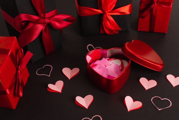 paper cut hearts near metallic box and wrapped presents on black - Fotó, kép