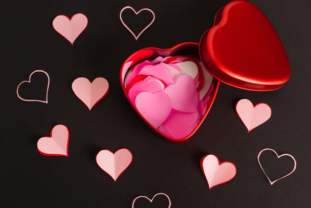 vista superior de corazones de papel rosa en caja metálica sobre negro - Foto, imagen
