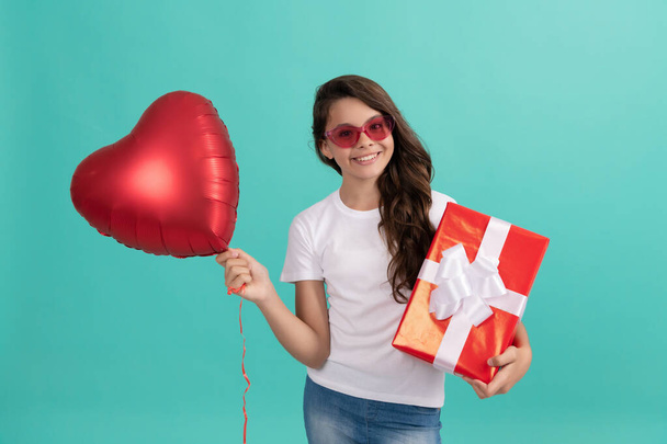 teen girl has birthday gift. child in sunglasses sharing box with ribbon. love heart. - Foto, immagini
