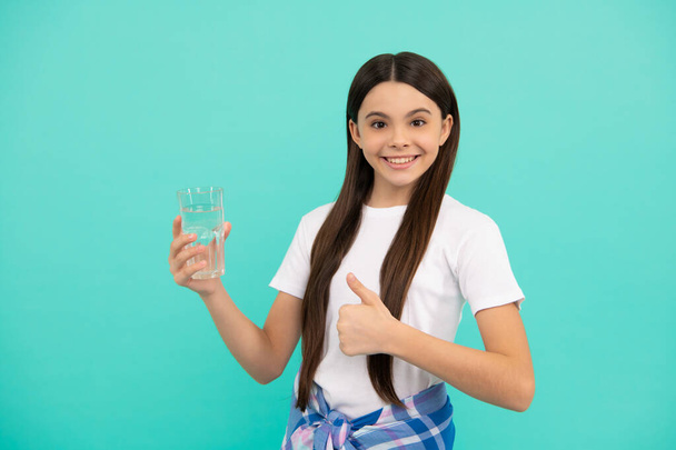 Ευτυχής έφηβος κορίτσι πίνουν νερό κρατήσει καθημερινή ισορροπία του νερού στο σώμα δείχνουν τον αντίχειρα επάνω, καθημερινά νερό. - Φωτογραφία, εικόνα