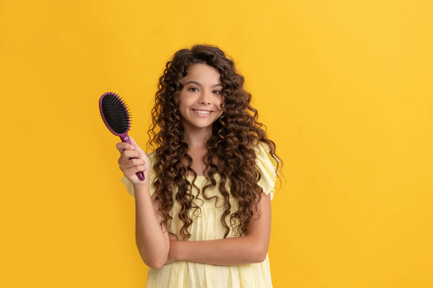 enfant heureux avec de longs cheveux bouclés tenant peigne brosse à cheveux pour peigner, beauté - Photo, image