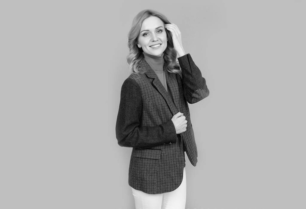 vrolijk blond vrouw in zaken casual brits jas op grijze achtergrond, schoonheid - Foto, afbeelding