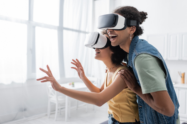 Positive african american couple in vr headsets gaming at home  - Photo, Image
