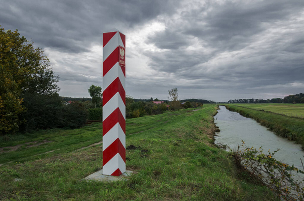 STAATSBORDERPOST - Die polnische Grenze ist mit Pfosten in den Nationalfarben gekennzeichnet  - Foto, Bild