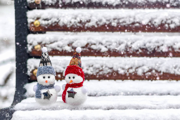 Mutlu noeller ve fotokopi alanı olan mutlu yeni yıl tebrik kartları Kış arka planında duran kırmızı, mavi şapkalı ve eşarplı iki küçük kardan adam Merhaba Ocak, Şubat konsepti - Fotoğraf, Görsel