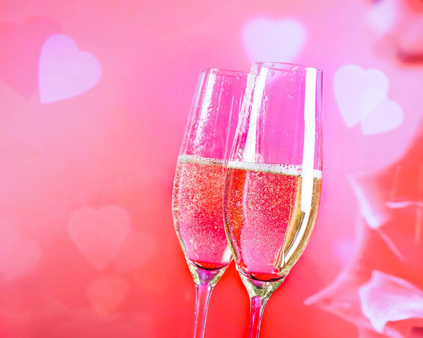 champagne flutes with golden bubbles on blur decorative hearts background - Valokuva, kuva
