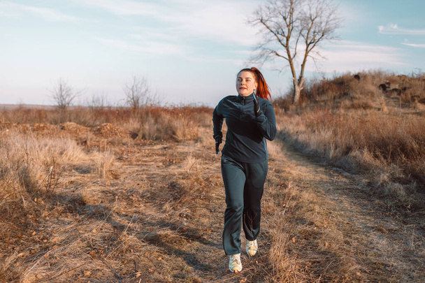 Corredor mujer caucásica corriendo en el parque de otoño. Concepto de estilo de vida saludable. Deportes activos - Foto, Imagen