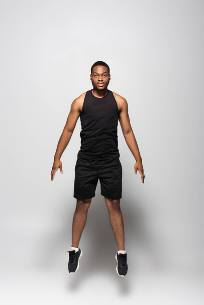 longitud completa del deportista afroamericano levitando sobre gris  - Foto, Imagen
