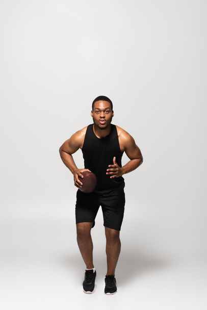 comprimento total do homem americano africano jogando rugby e correndo em cinza  - Foto, Imagem