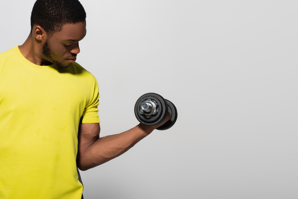 deportista afroamericano haciendo ejercicio con mancuerna aislada en gris  - Foto, imagen
