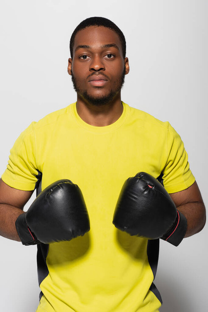 若いアフリカ系アメリカ人のスポーツマンがグレーで隔離されたボクシンググローブで - 写真・画像