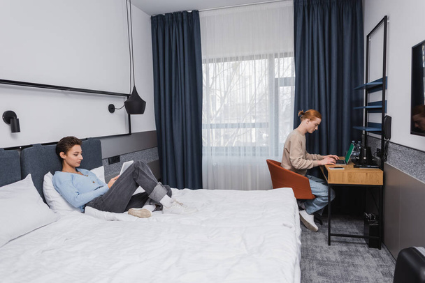 Young couple using devices in modern hotel room  - Photo, Image