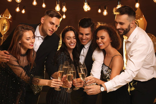 Happy friends with glasses of sparkling wine celebrating New Year indoors - Photo, Image