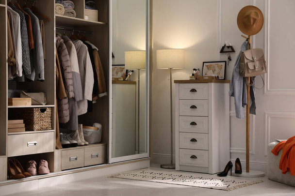 Wardrobe closet with different stylish clothes, shoes and home stuff in room - Foto, Imagen