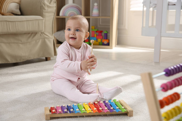 Cute baby girl playing with xylophone on floor at home - Valokuva, kuva
