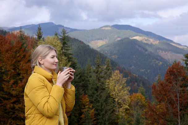 Young woman with mug of hot drink in mountains - Valokuva, kuva