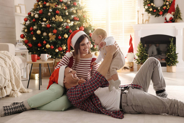 Happy family with cute baby on floor in room decorated for Christmas - Photo, image