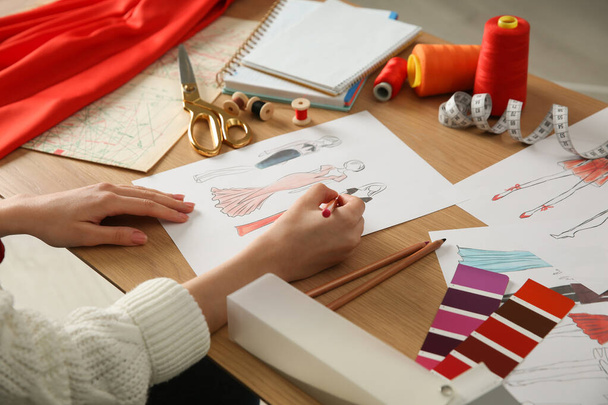 Fashion designer creating new clothes in sketchbook at wooden table, closeup - Foto, imagen