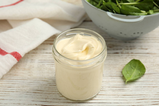 Jar of delicious mayonnaise and fresh spinach on white wooden table - Fotografie, Obrázek