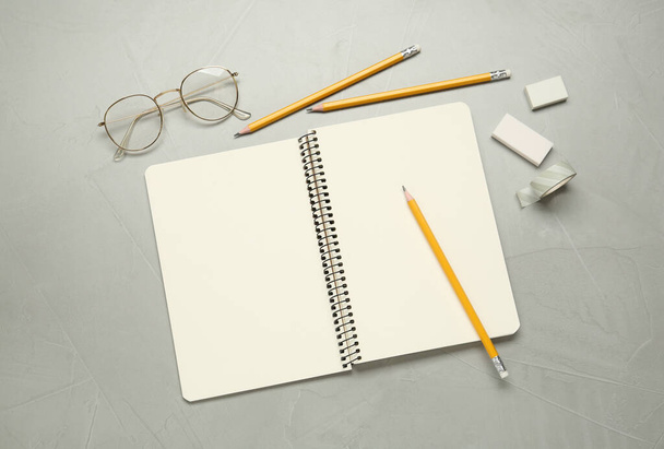 Flat lay composition with sketchbook, glasses and stationary on light grey table - Foto, Imagen