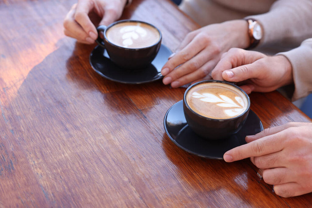 Couple with cups of aromatic coffee at wooden table, closeup - Foto, Imagem