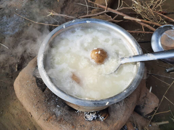 薪ストーブでご飯を炊く。インドの村で伝統的な料理スタイル。ご飯と一緒にジャガイモも沸騰しています。木造火災. - 写真・画像