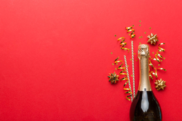 fles champagne met glazen en kleurrijke confetti op gekleurde achtergrond. bovenaanzicht flay lay. - Foto, afbeelding