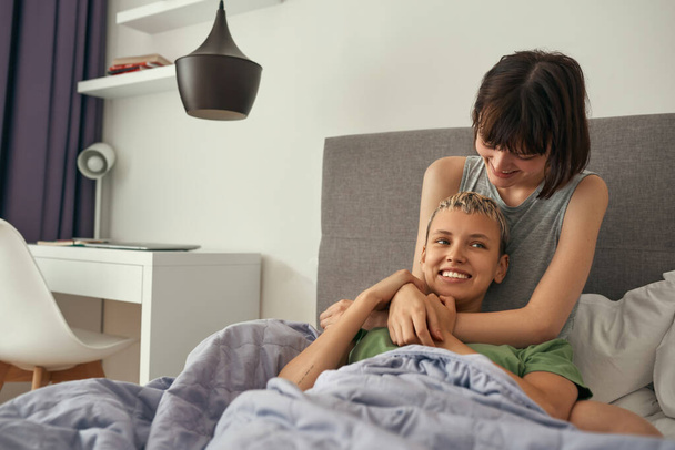 Young lesbians hugging on bed together at home - Fotografie, Obrázek