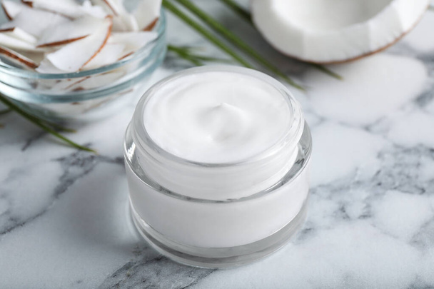 Jar of body cream with coconut on white marble table, closeup - Photo, image